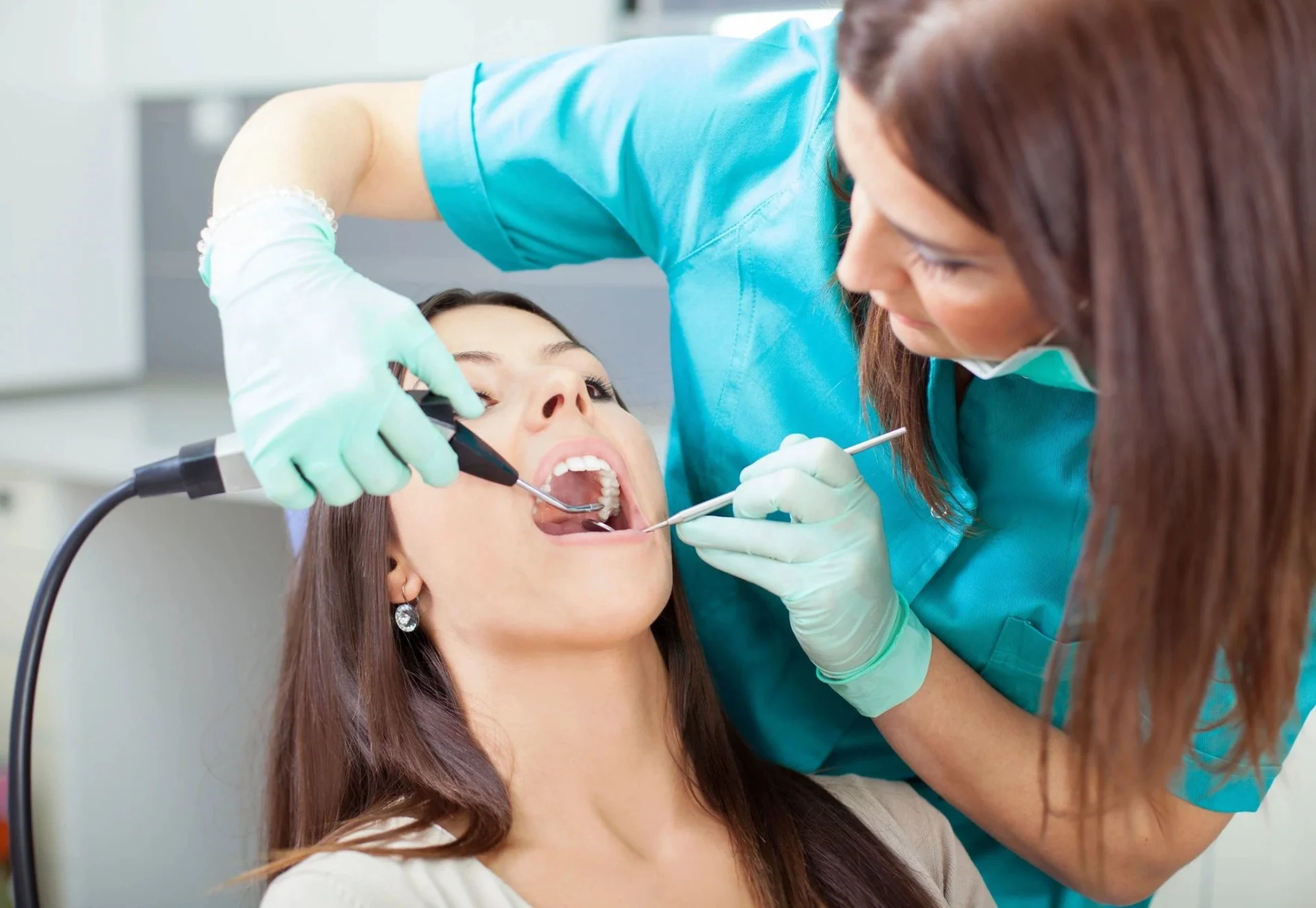 A woman getting her teeth checked by an dentist.